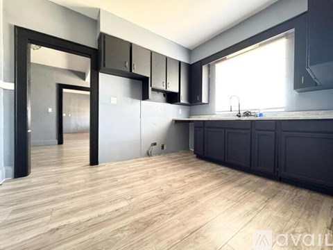 A kitchen with black cabinets and a wooden floor.