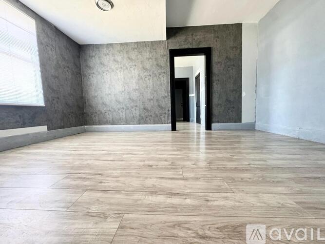 A spacious room with a marble floor and a doorway leading to another room.