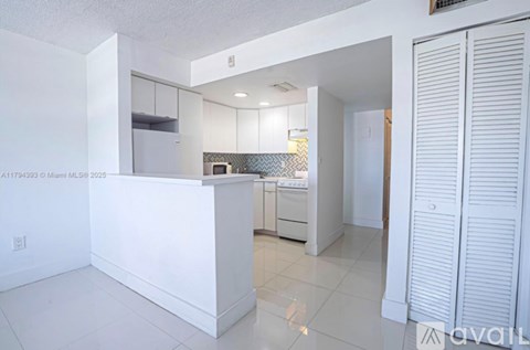 A kitchen with white cabinets and a white island.