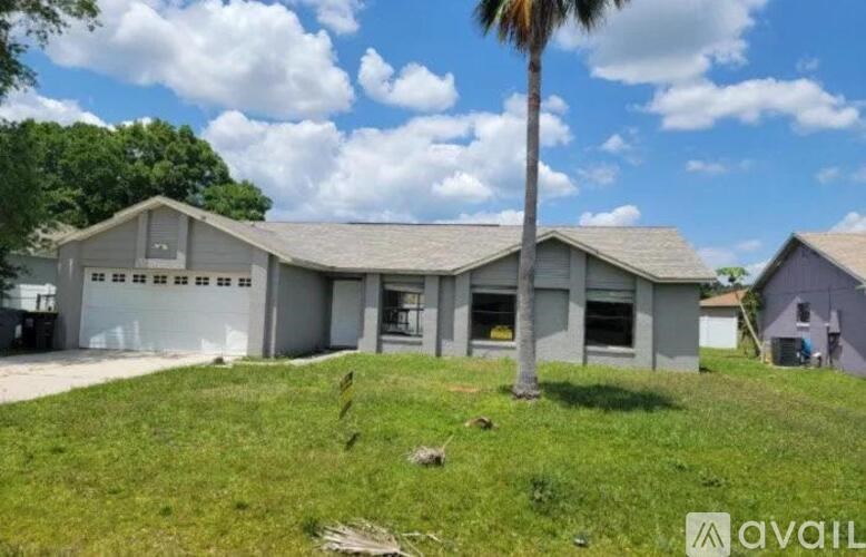 A house with a garage and a palm tree in front.