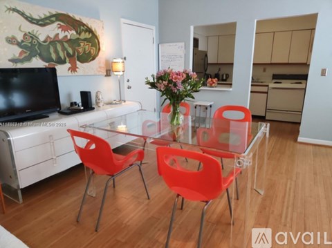 A modern dining room with a glass table and red chairs.