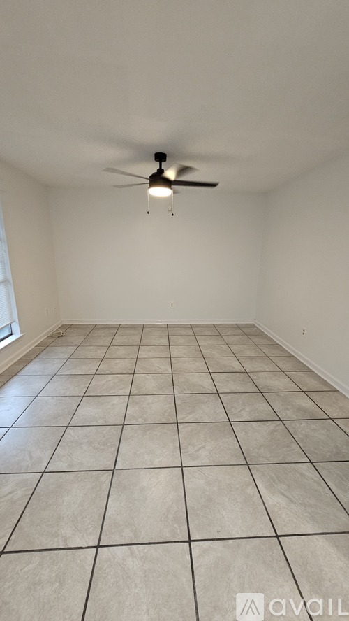 A room with a ceiling fan and tiled flooring.