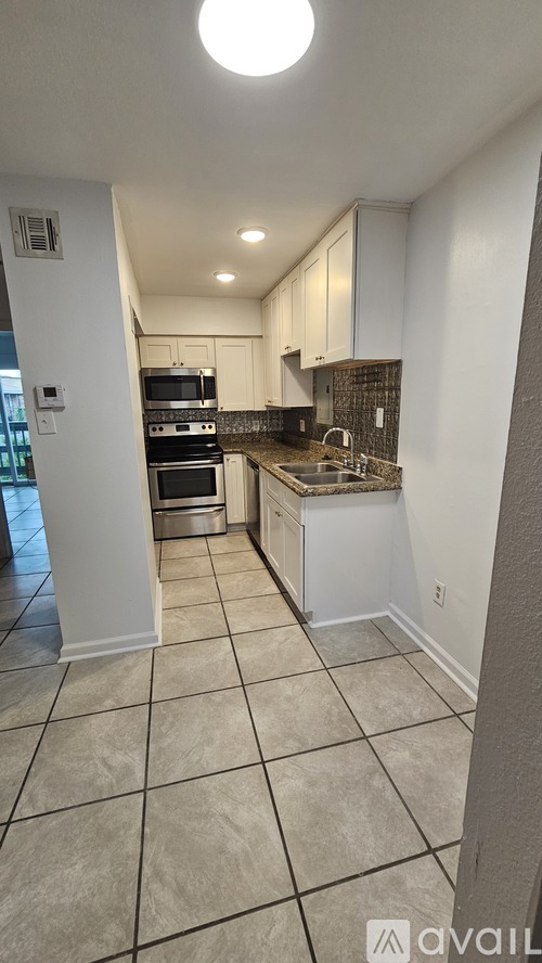 A kitchen with white cabinets and a tiled floor.