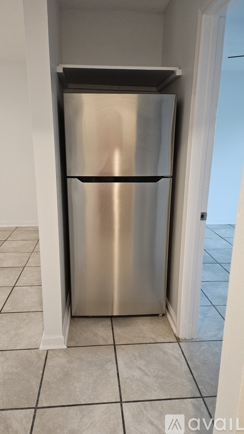A stainless steel refrigerator in a room with white walls and tiled flooring.
