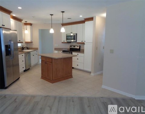 A kitchen with a wooden island and stainless steel appliances.