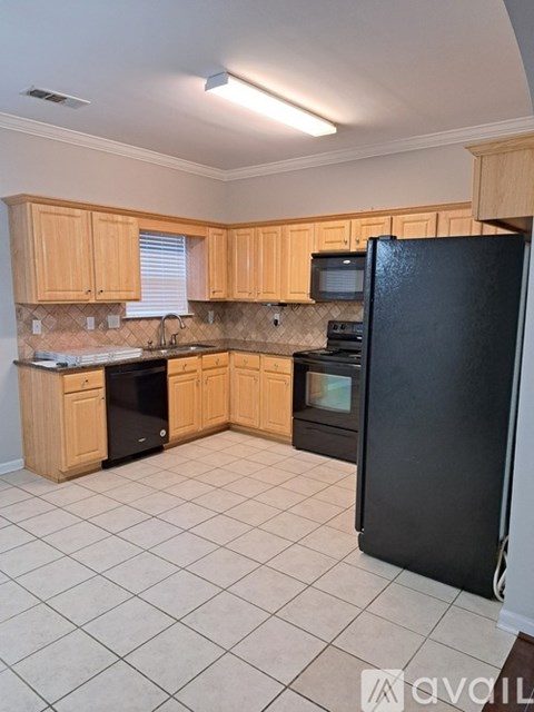 A kitchen with wooden cabinets and a black refrigerator.