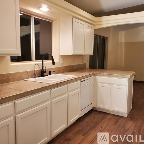 A kitchen with white cabinets and a brown countertop.