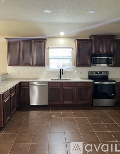 A kitchen with brown cabinets and a tiled floor.