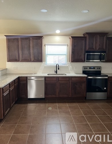 A kitchen with brown cabinets and a tiled floor.