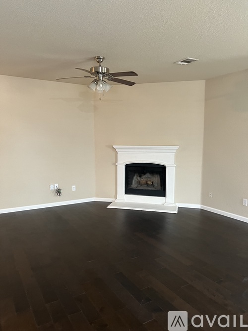 A living room with a fireplace and a ceiling fan.
