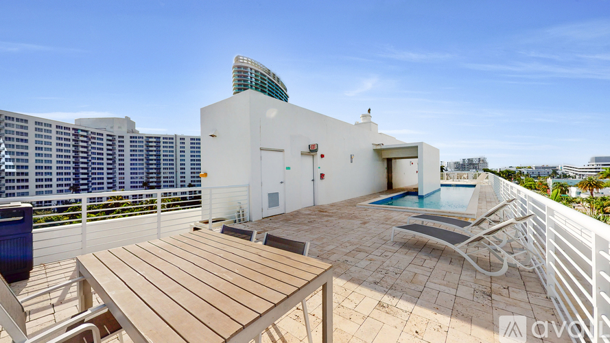 A modern white building with a pool and a wooden table.