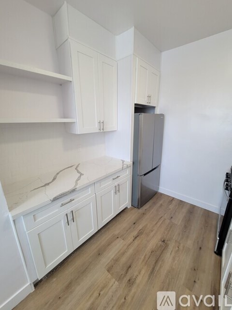 A kitchen with white cabinets and a wooden floor.