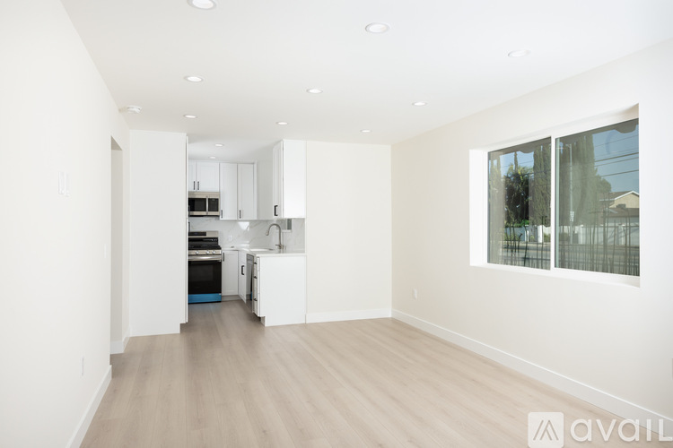 A spacious kitchen with white cabinets and a wooden floor.