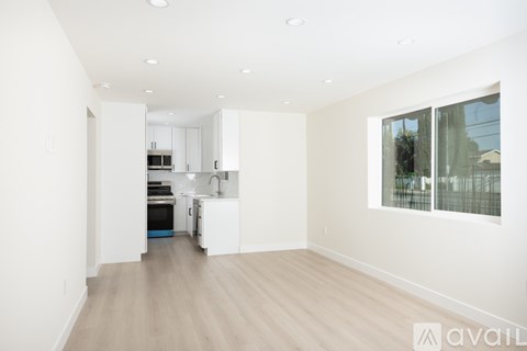 A spacious kitchen with white cabinets and a wooden floor.