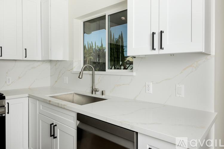 A kitchen with white cabinets and marble countertops.