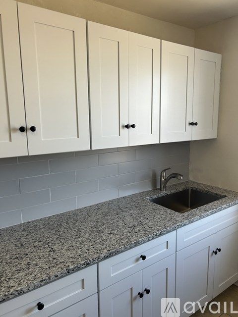 A kitchen with white cabinets and a granite countertop.