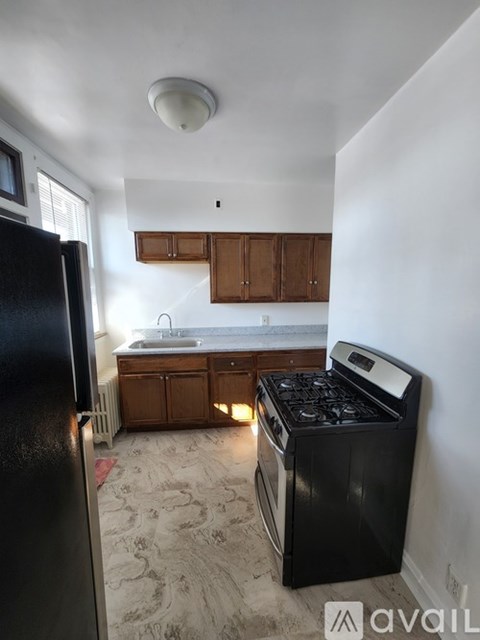 A kitchen with a black fridge and a black stove top oven.