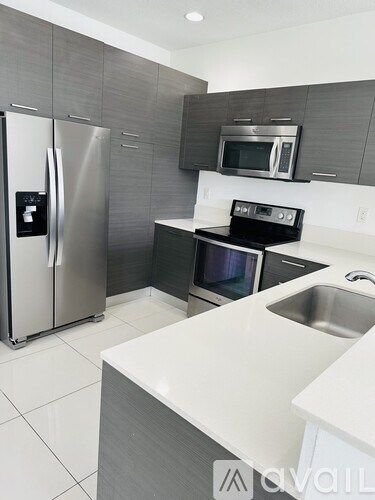 A modern kitchen with a stainless steel refrigerator and microwave.