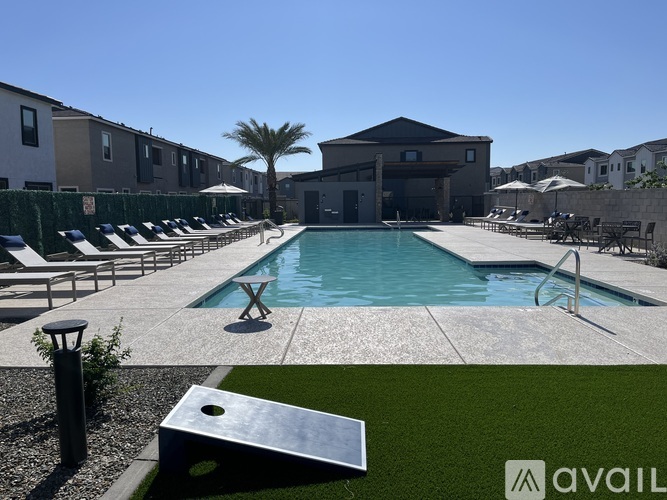 A pool surrounded by lounge chairs and umbrellas with a building in the background.