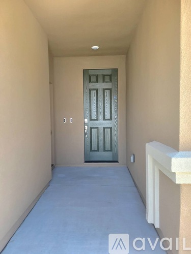 A hallway with a closed door and a white railing on the right side.