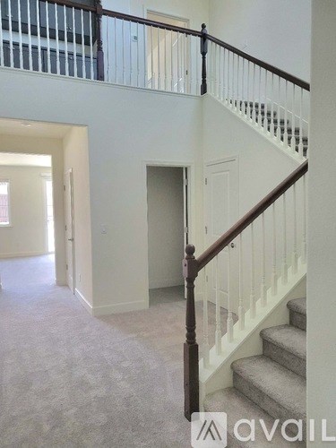 A staircase with a wooden handrail and white balusters leads to a doorway.