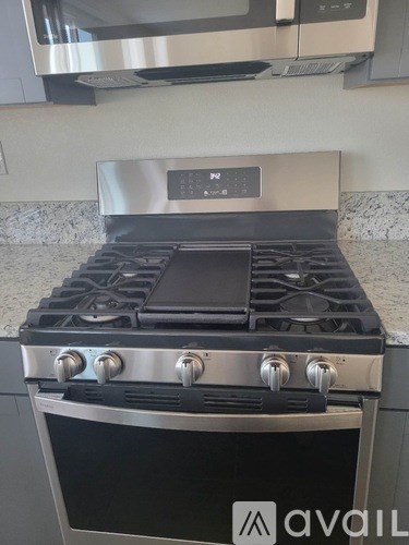 A stainless steel gas stove with a digital control panel is in a kitchen.