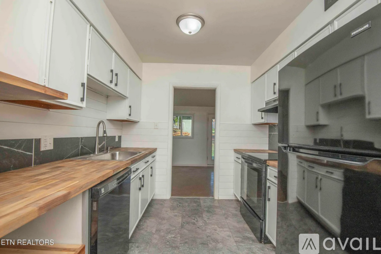 A modern kitchen with white cabinets and a wooden countertop.