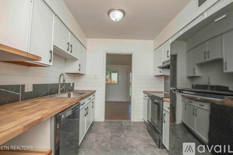 A modern kitchen with white cabinets and a wooden countertop.