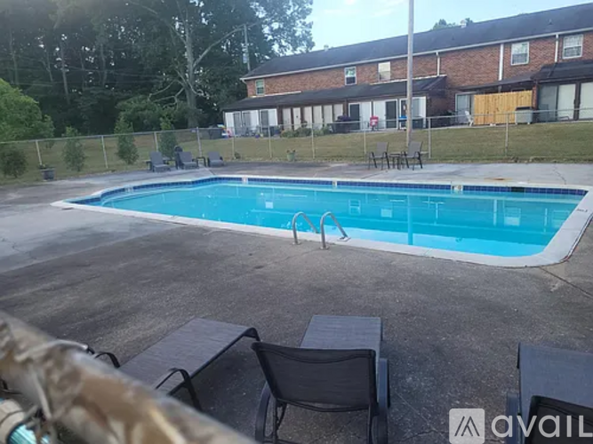 A pool with a table and chairs in front of a house.