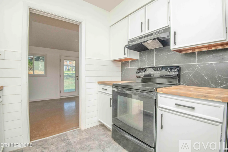 A kitchen with white cabinets and a black stove top oven.