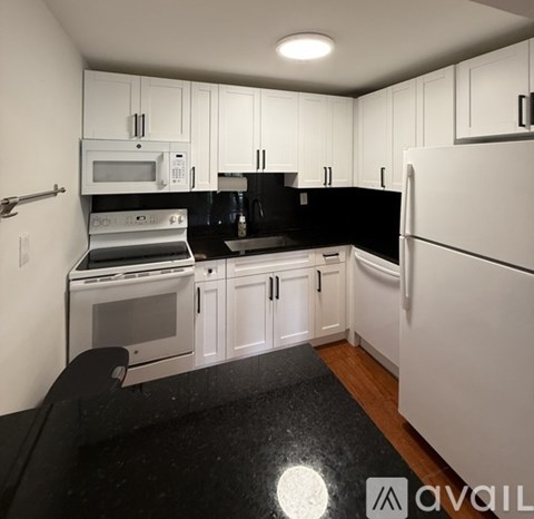 A kitchen with white cabinets and black countertops.