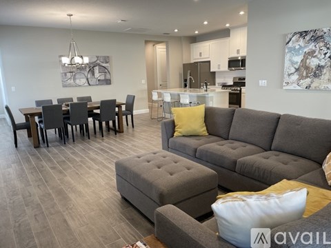 A modern living room with a grey sofa and a dining table set up.