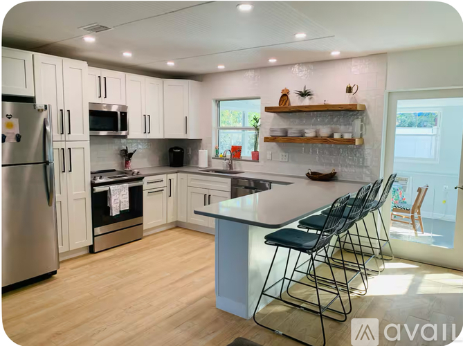 A kitchen with a refrigerator, microwave, oven, and sink.
