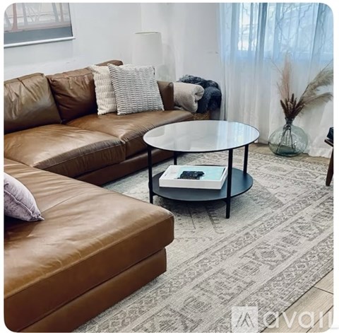 A living room with a brown leather sofa and a glass coffee table.