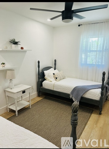 A bedroom with a black bed and a white nightstand.