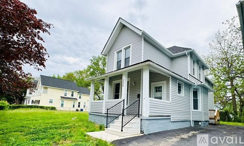 A two-story house with a front porch and a black railing.