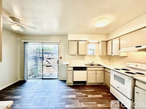 A kitchen with white appliances and wooden floors.