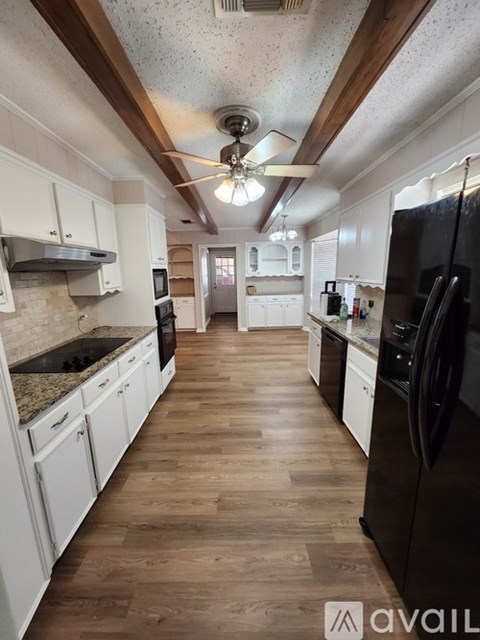 A kitchen with white cabinets and a black fridge.