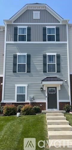 A grey house with a black door and a small porch.