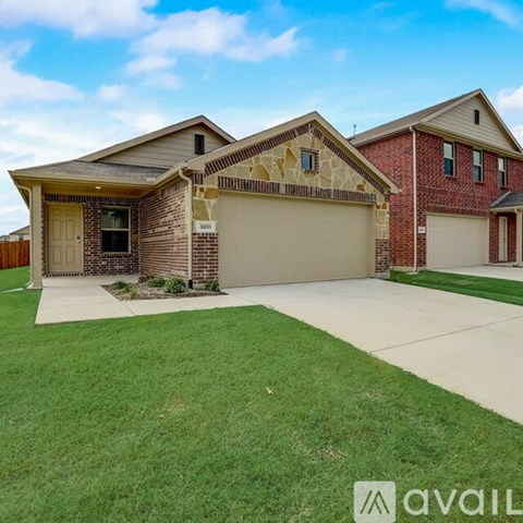 A house with a brown brick facade and a beige garage door is for sale.