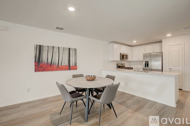 A dining room with a white table and chairs and a painting on the wall.