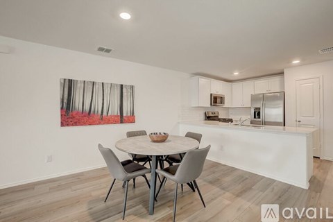 A dining room with a white table and chairs and a painting on the wall.