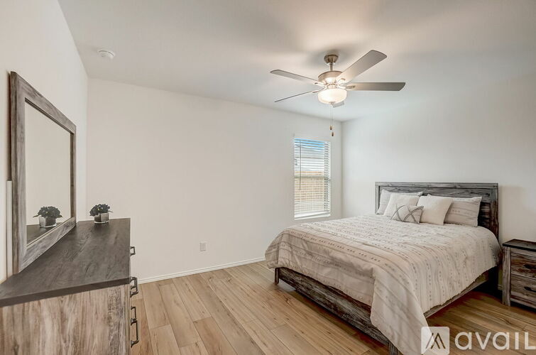 A bedroom with a large bed, a ceiling fan, and a wooden dresser.
