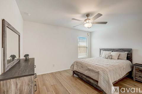 A bedroom with a large bed, a ceiling fan, and a wooden dresser.
