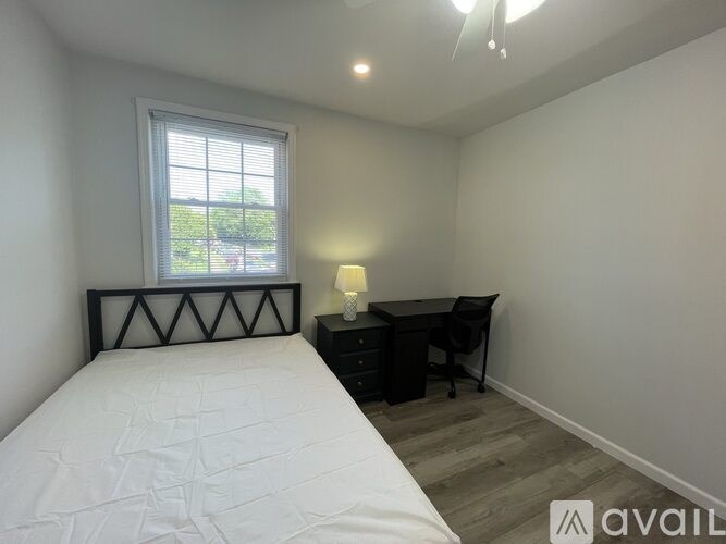 A bedroom with a bed, desk, and chair.