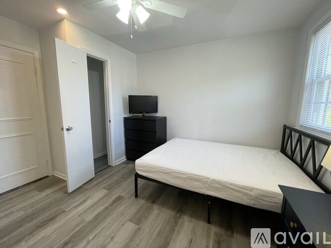 A bedroom with a bed, dresser, and television.
