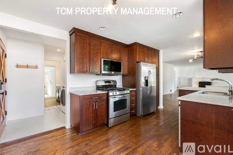 A kitchen with wooden cabinets and stainless steel appliances is available for rent.
