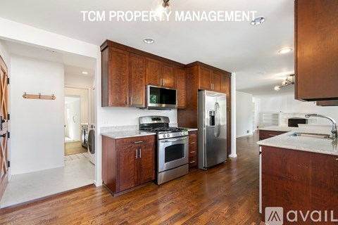 A kitchen with wooden cabinets and stainless steel appliances is available for rent.