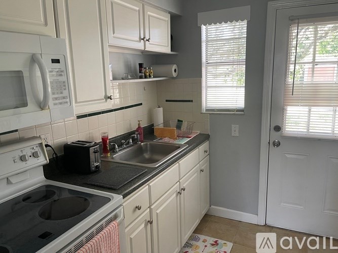 A kitchen with white cabinets and a black stove top.