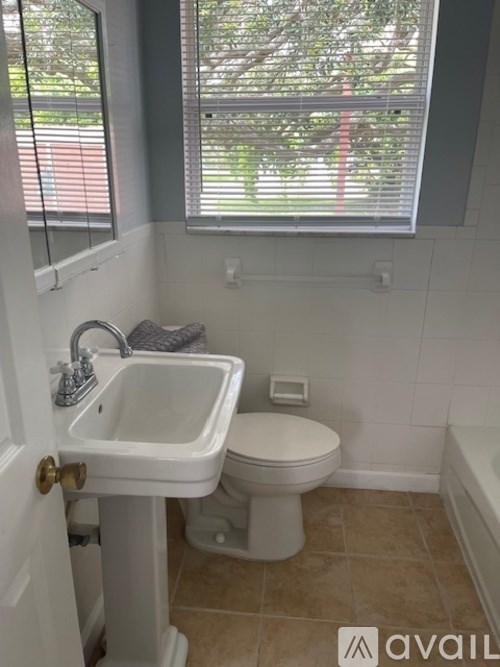 A bathroom with a toilet, sink, and window.